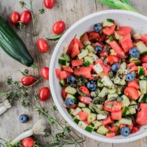Frischer Gemüsesalat mit Tomaten, Gurken und Heidelbeeren, perfekt für eine gesunde Mahlzeit oder einen Snack.