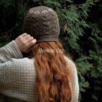 Strickset für Alyssum Cap mit braunem Garn und Anleitung, auf einem Baum sitzend.