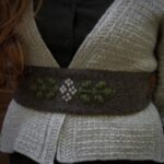 Strickset für ALYSSUM KERCHIEF mit Garn und Anleitung, gezeigtes Muster auf einem Wollstück.