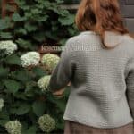 Strickjacke in Grau mit Blumen im Garten, passend zum Strickset für Alyssum Kerchief.