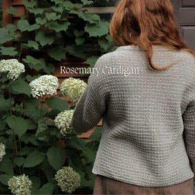 Strickjacke in Grau mit Blumen im Garten, passend zum Strickset für Alyssum Kerchief.