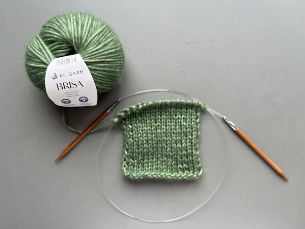 Strickset mit grünem Garn und Anleitung für A-Linien-Pullover 'Tusheti' im Wollke-Shop.